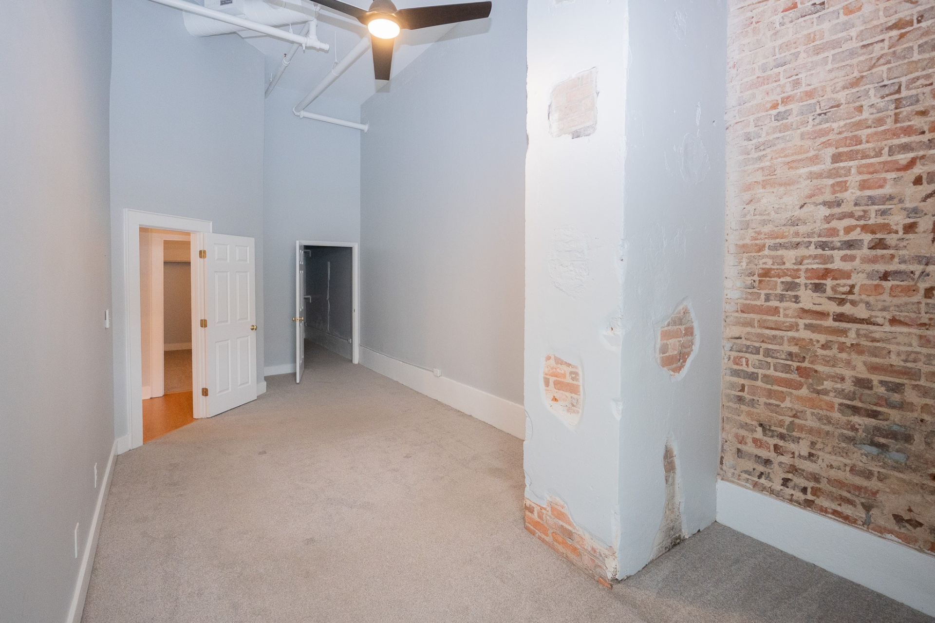 Loft interior with exposed red brick column, ceiling fan and exposed pipes