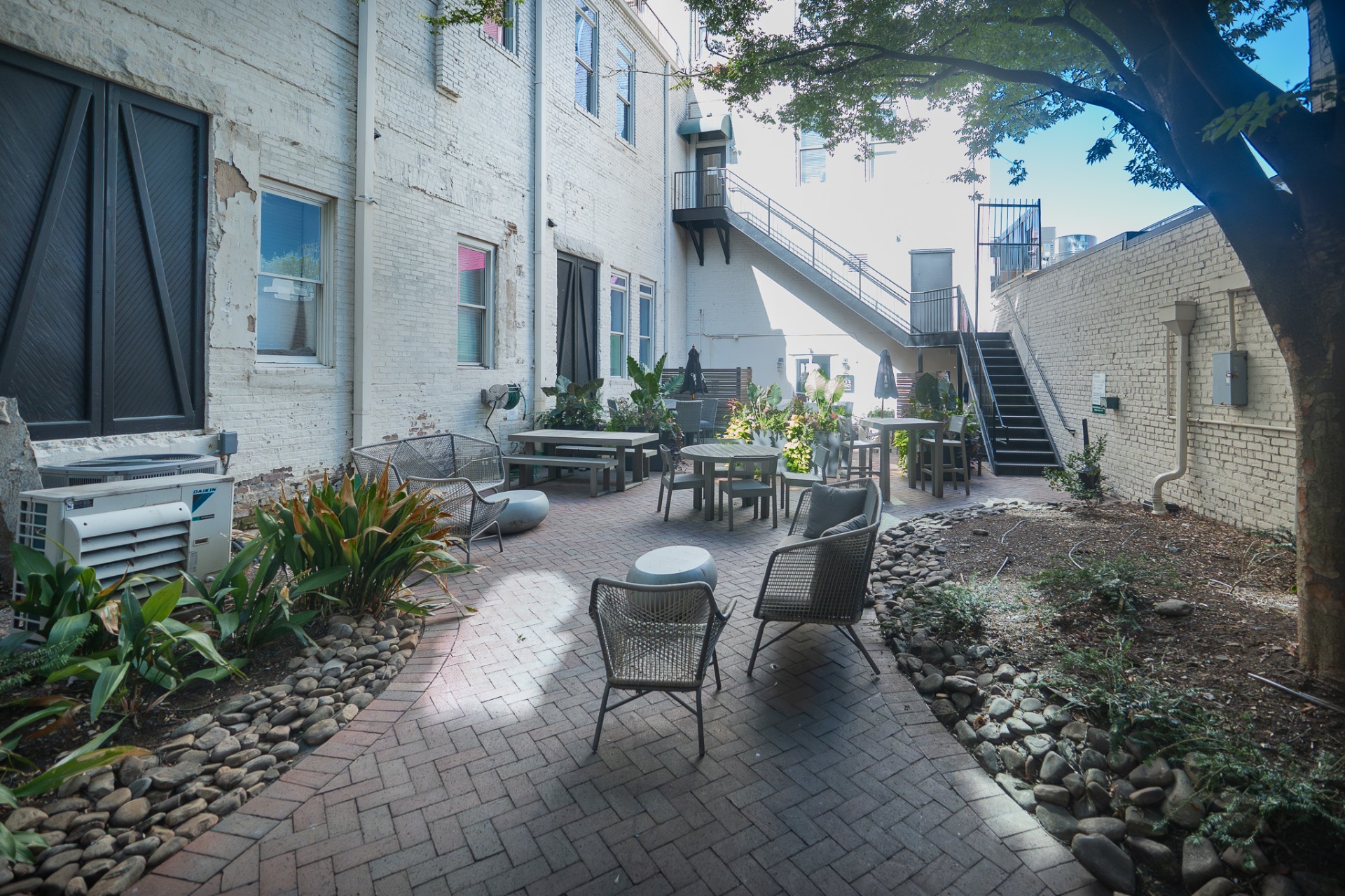 Brick courtyard with tables, chairs, plants and exterior stairs