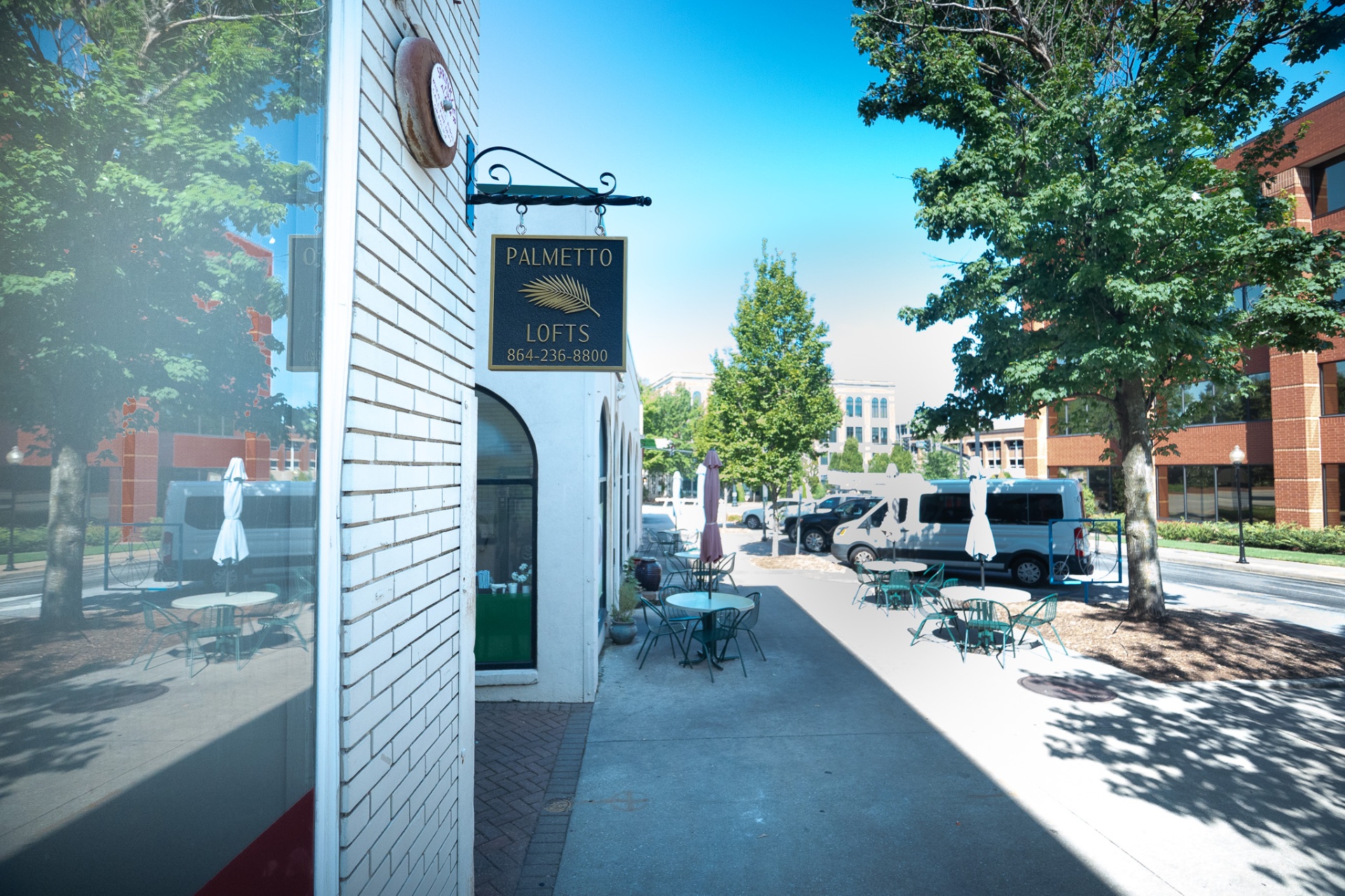 Downtown sidewalk outside Palmetto Lofts with outdoor cafe seating and trees