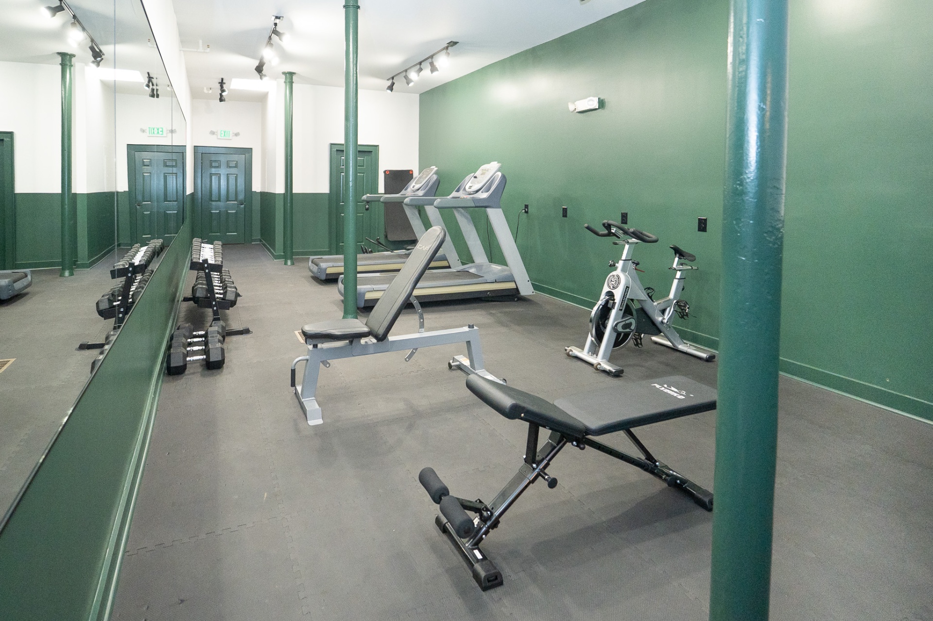 Fitness room with treadmills, stationary bikes, dumbbells and a weight bench